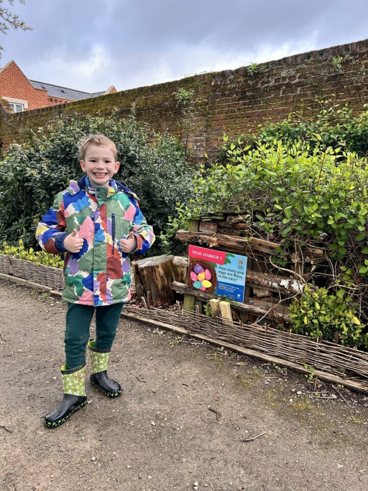 Boy next to trail marker outside with thumbs up