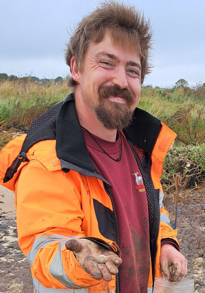 A dig team member with an unearthed musket ball