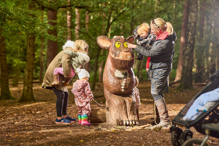 Two adults and small children around The Gruffalo's Child sculpture