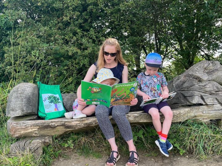 Mum and two children sit on a bench reading two books