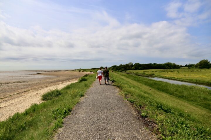 Two people walking on the sea wall path at Cudmore Grove