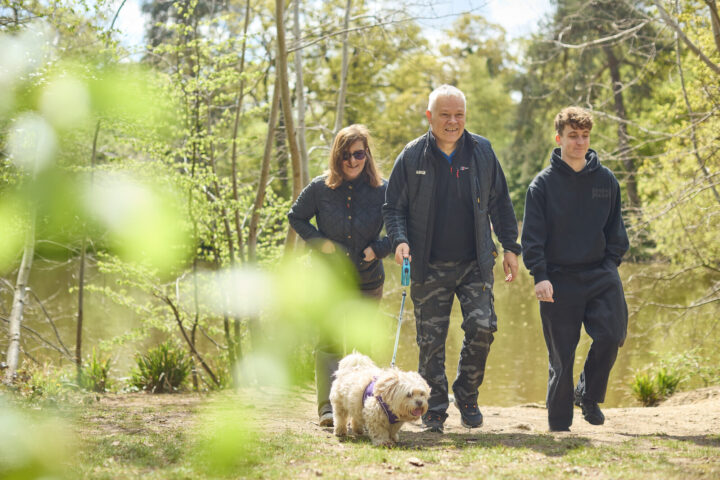 An older couple and son walking their dog.