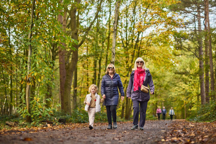 Three generations from young girl, mum and grandma walk in the woods