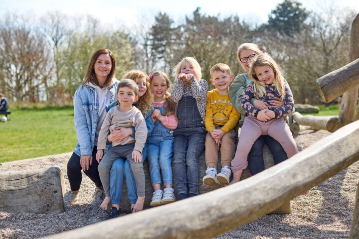 Children and their parents sitting on play equipment at Cudmore Grove