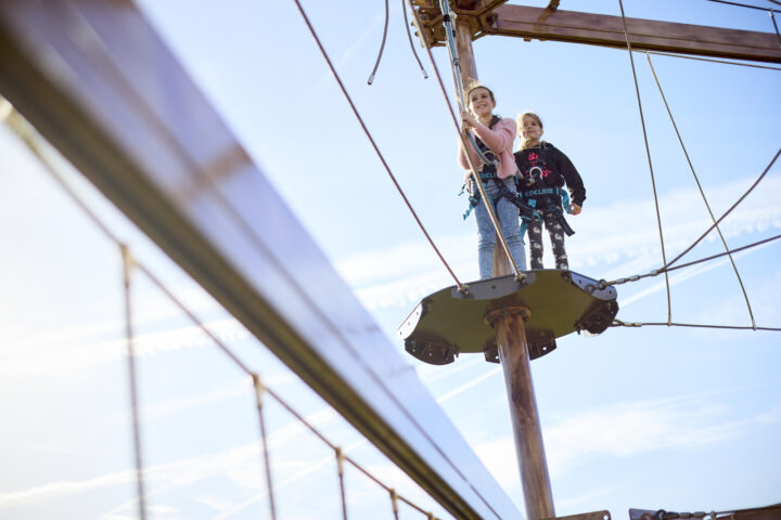 Two people on a platform and beams against a blue sky