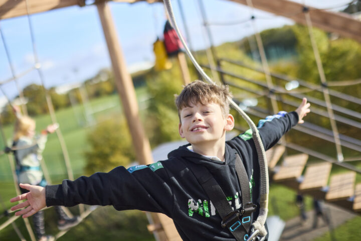 Man and boy on high ropes course against blue sky