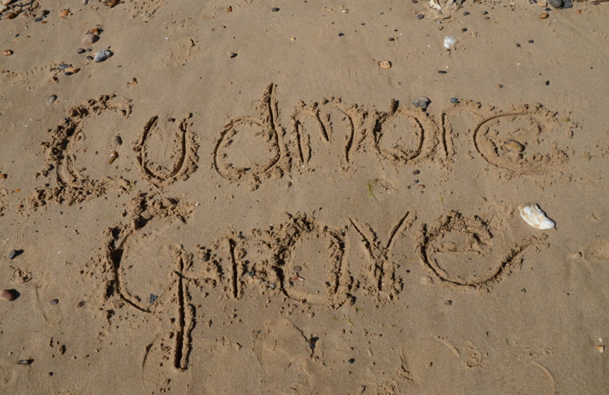The words Cudmore Grove written in the sand