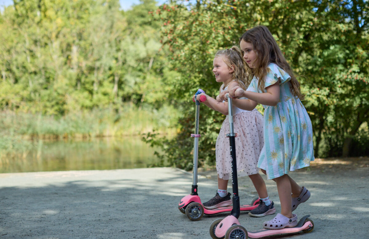 Two young girls scooting by the lake