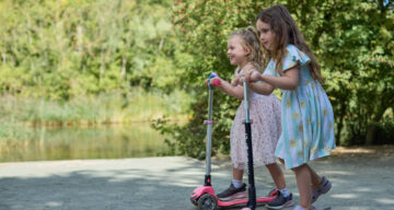 Two young girls scooting by the lake