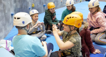 Children sitting near a climbing wall