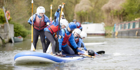 A group of children paddling on a stand up raft