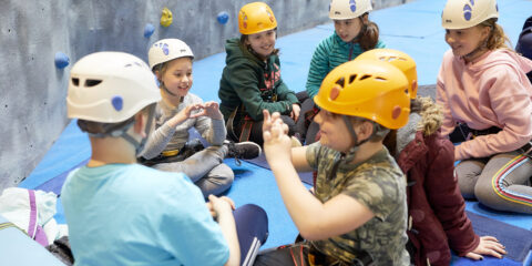 Children sitting near a climbing wall